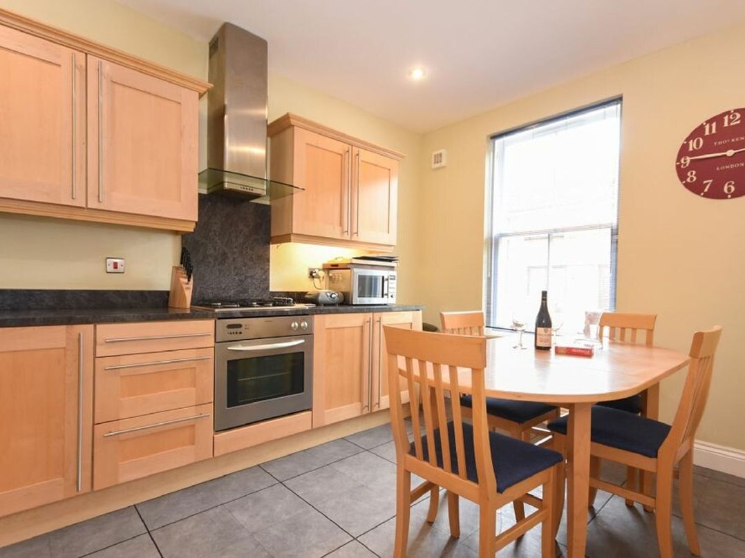 A kitchen with wooden cabinets and a dining table with four chairs at Churchside in Alnwick