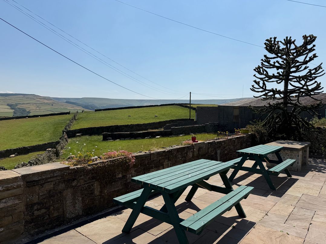 An outdoor area with picnic tables and fields at Stone & Fleece Cottage in Holmfirth
