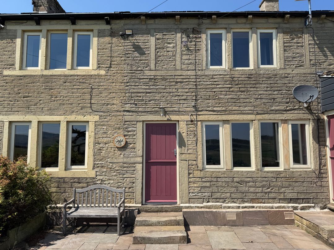 A house with a purple front door and windows at Stone & Fleece Cottage in Holmfirth