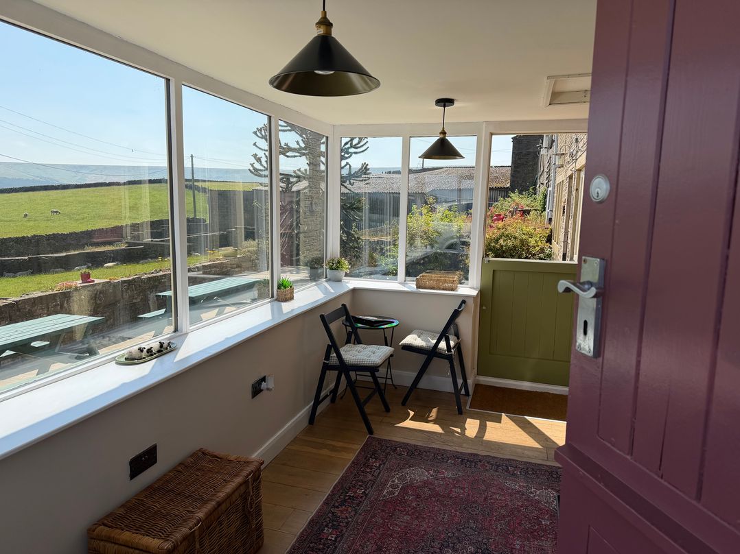 A conservatory with glass windows and seating at Stone & Fleece Cottage Holmfirth