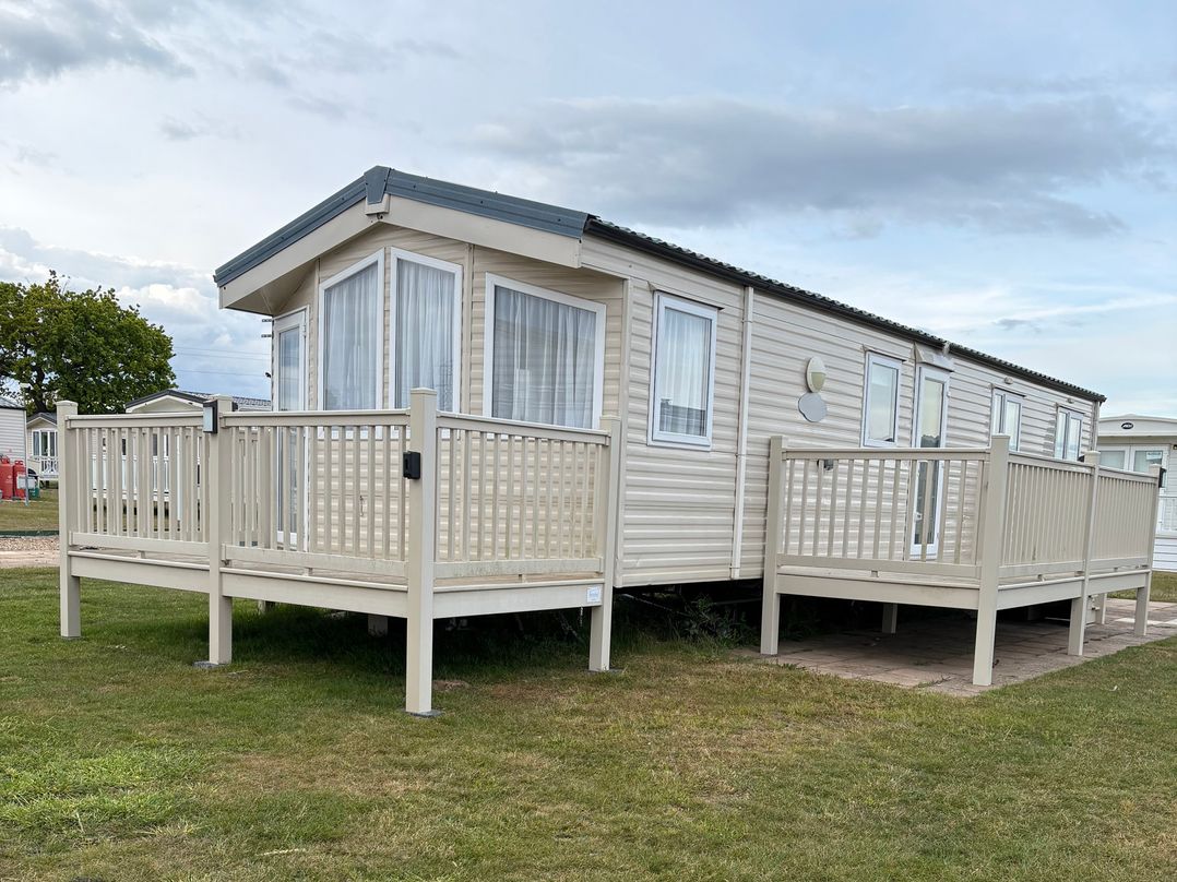 A mobile home with a deck and steps at Caravan 607 in Clacton-On-Sea