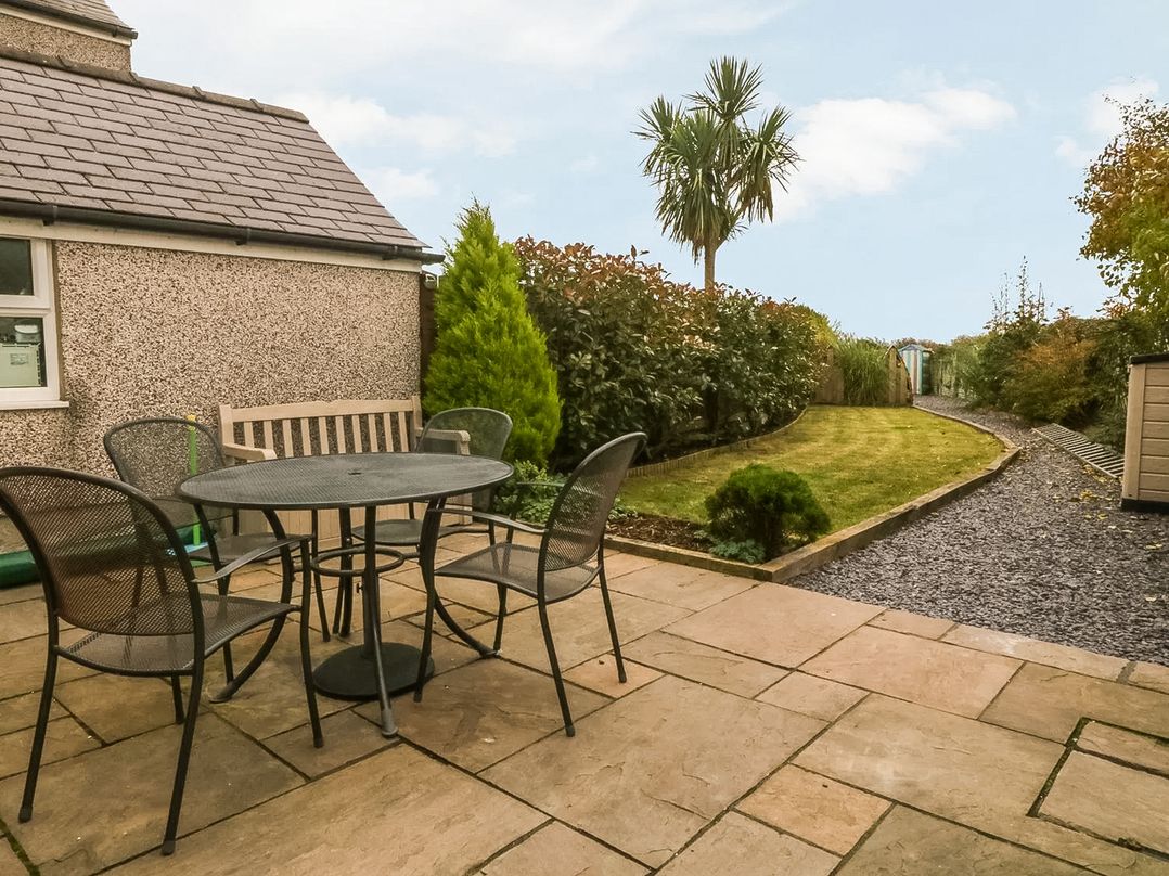 A garden with a table and chairs at Rhianfa in Newborough