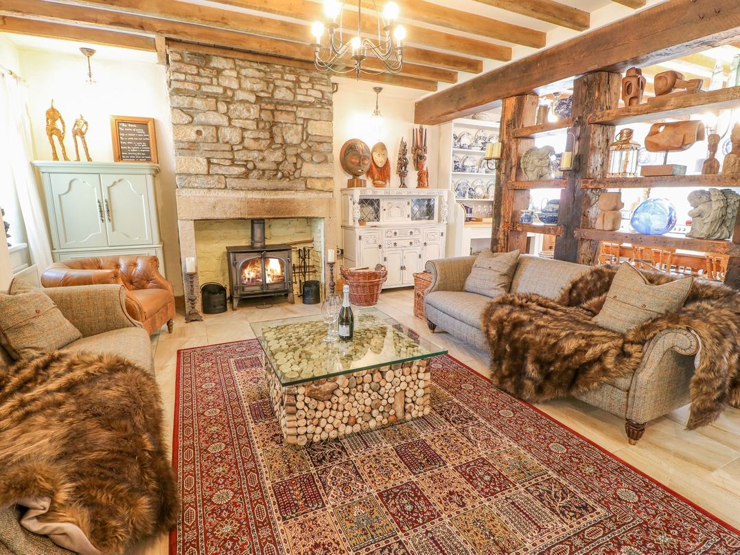 A living room with a stone fireplace a glass coffee table and two sofas at Shaftoe Mews in Haydon Bridge