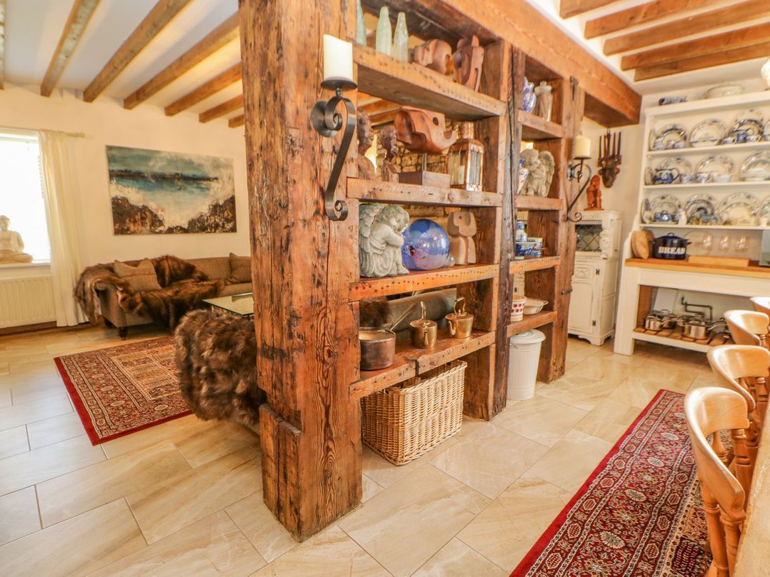 A room with wooden beams shelves displaying ceramics and decorations a sitting area with sofa and artwork on the wall at Shaftoe Mews in Haydon Bridge