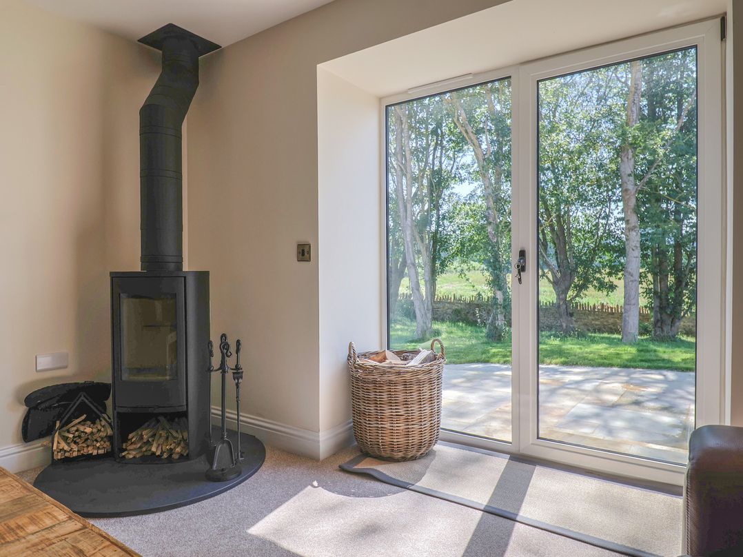 A snug with a wood stove and a basket at The Fox Den in East Coker
