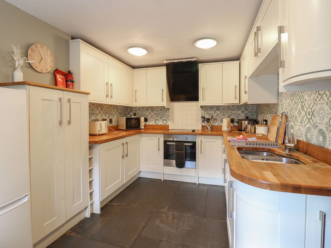 A kitchen with cabinets and appliances at Cader Cottage in Dolgellau