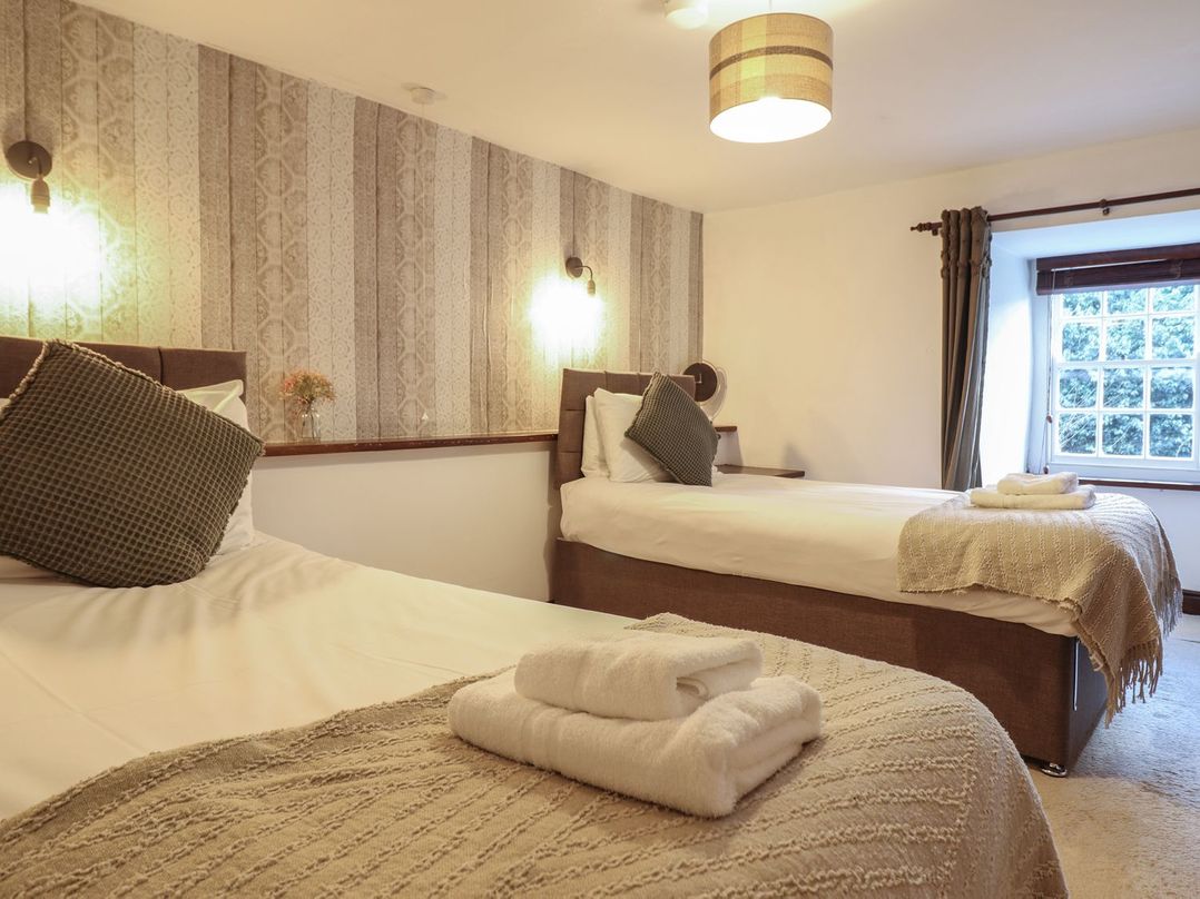 A bedroom with two single beds and a window at Cader Cottage in Dolgellau