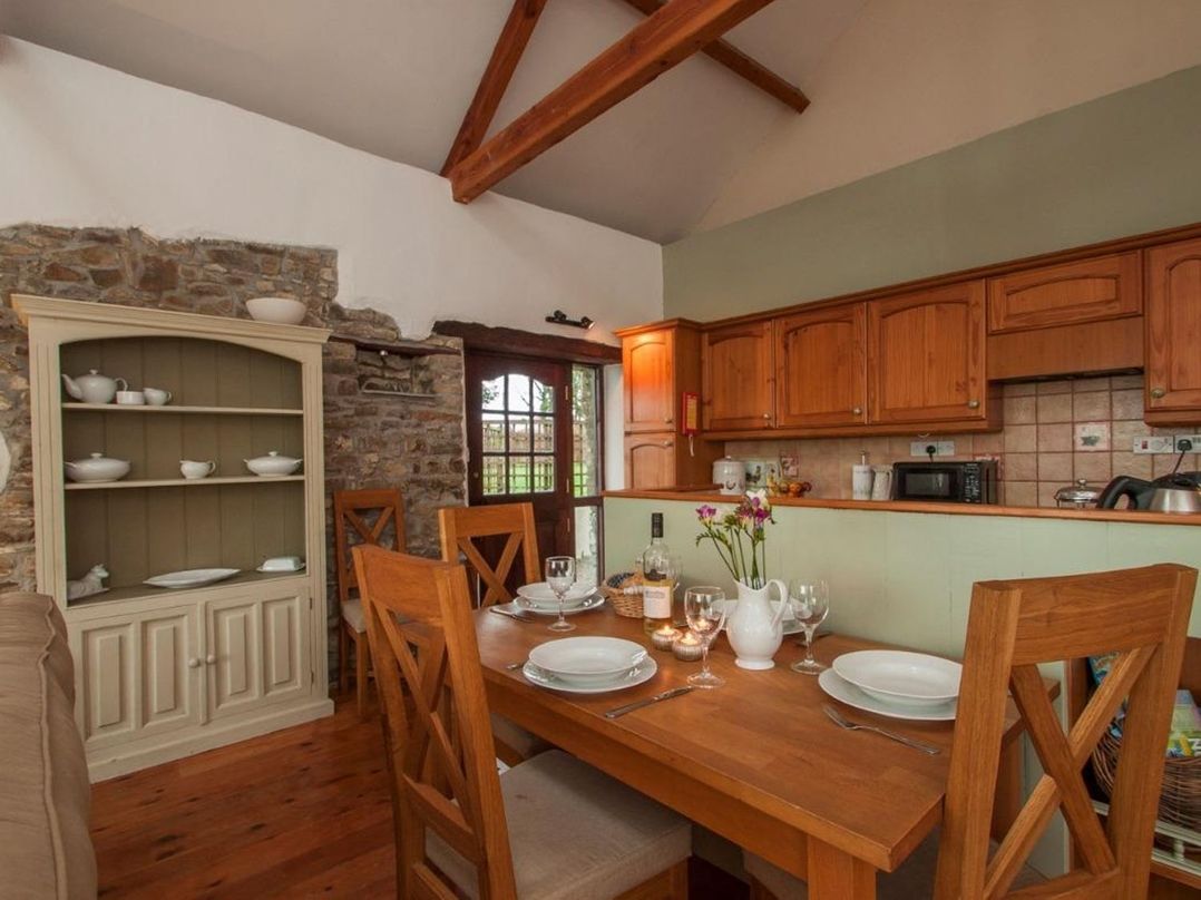 A kitchen with a wooden dining table and chairs at Billy's Barn in Bradworthy