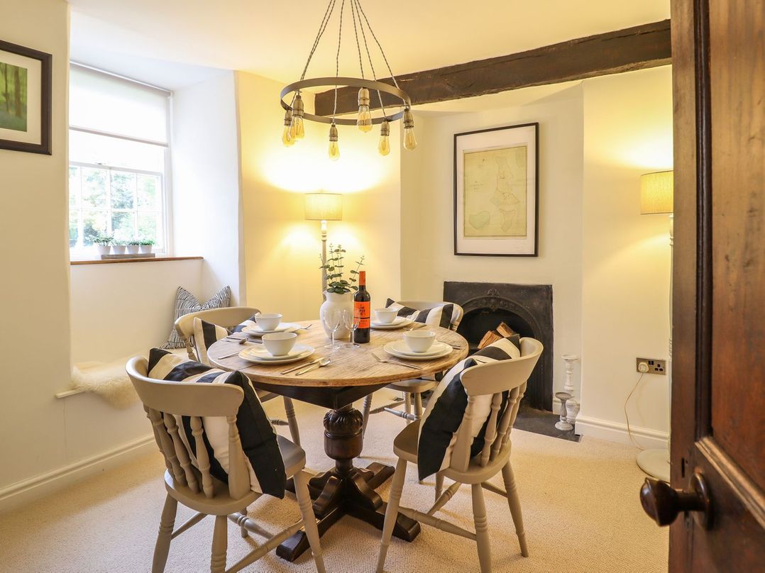 A dining room with a round table and chairs at Bwthyn Canol in Llanfair