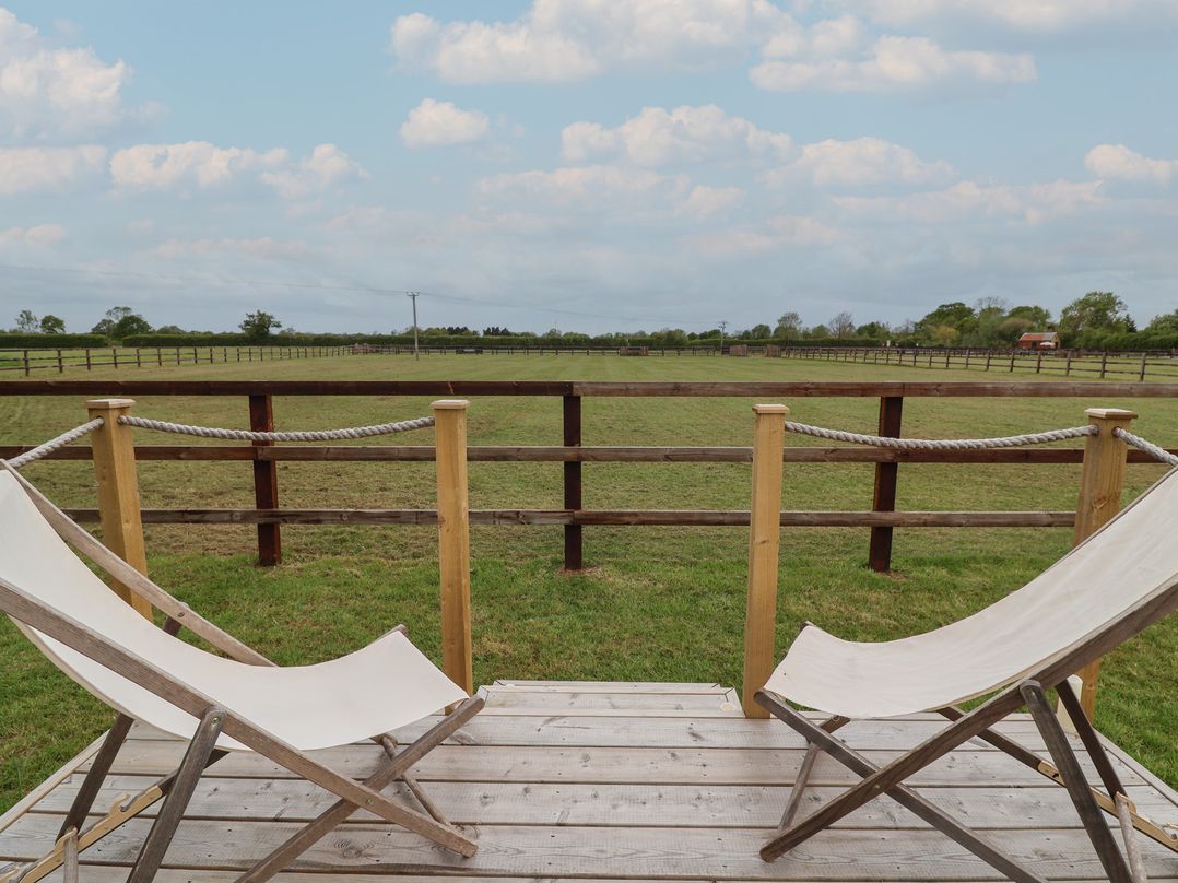 An outdoor area with chairs overlooking a grassy field at Bell 1 Shades Farm near Minety