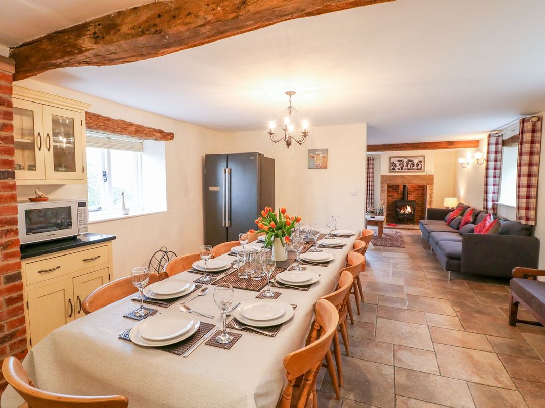 A dining room with a long table and fireplace at The Barn in Wirksworth