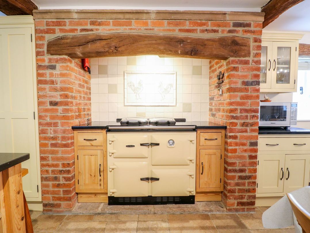 A kitchen with a brick wall and a cooker at The Barn in Wirksworth