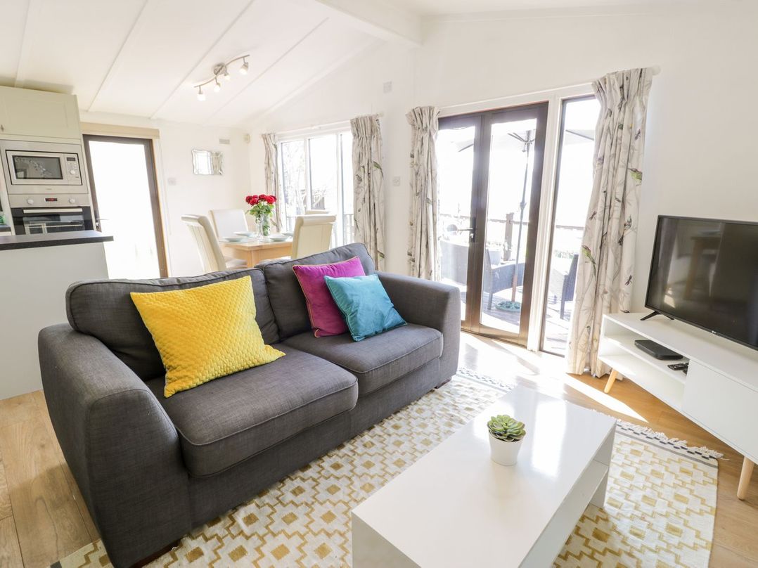 A living room with a sofa and a dining area at Summertime Lodge Rhyd-y-Foel near Abergele