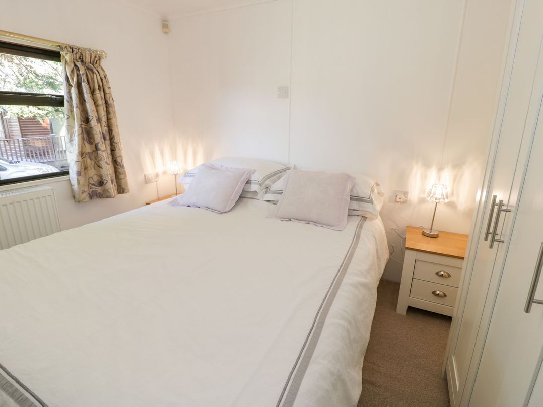 A bedroom with a double bed and curtains at Summertime Lodge Rhyd-y-Foel near Abergele