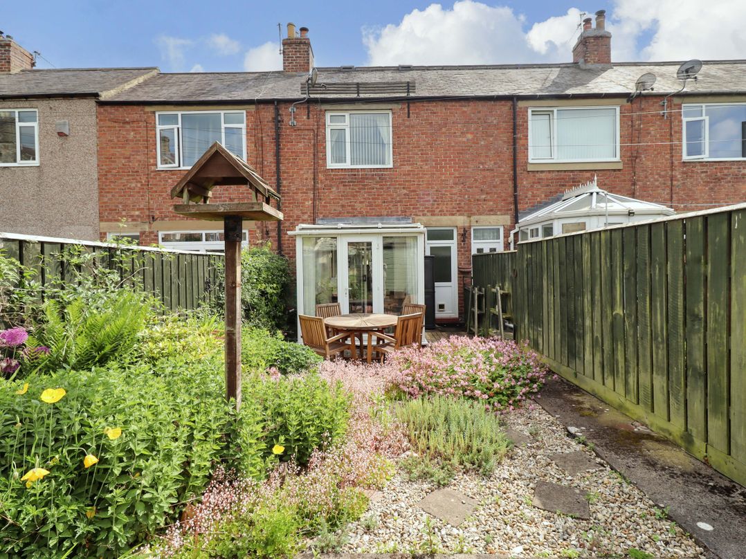 A garden with seating area and greenery at Rose Briar Cottage in Morpeth