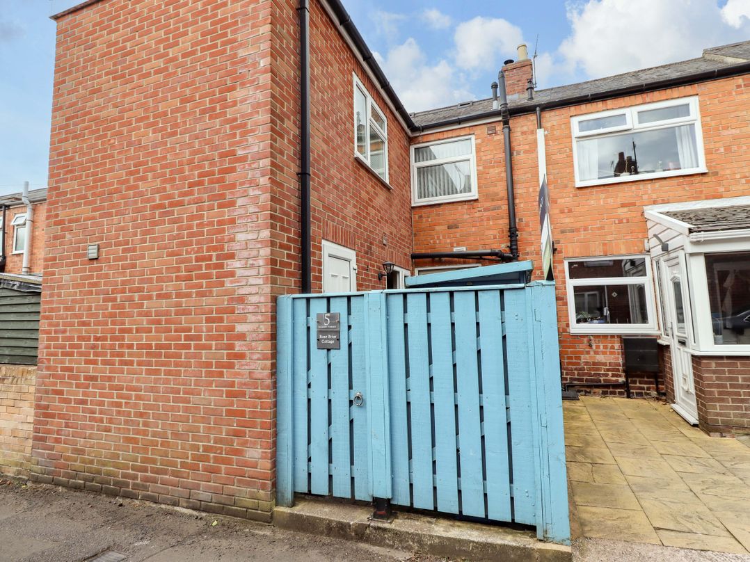 An outdoor area with a brick wall and blue gate at Rose Briar Cottage in Morpeth
