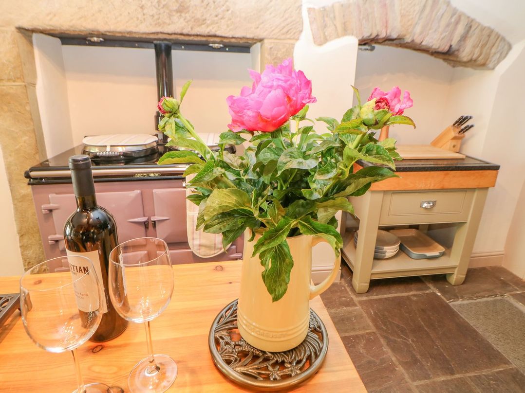 A kitchen with flowers, wine glasses, and a kitchen range at Billy Whiskey's in Tideswell