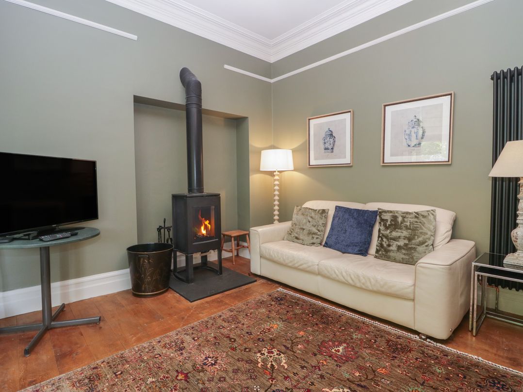 A living room with a wood stove and television at The Boundary in Windermere