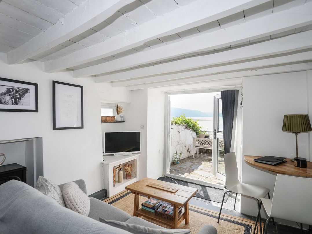 A living room with a sofa, television, and coffee table at The Ingle in Barmouth