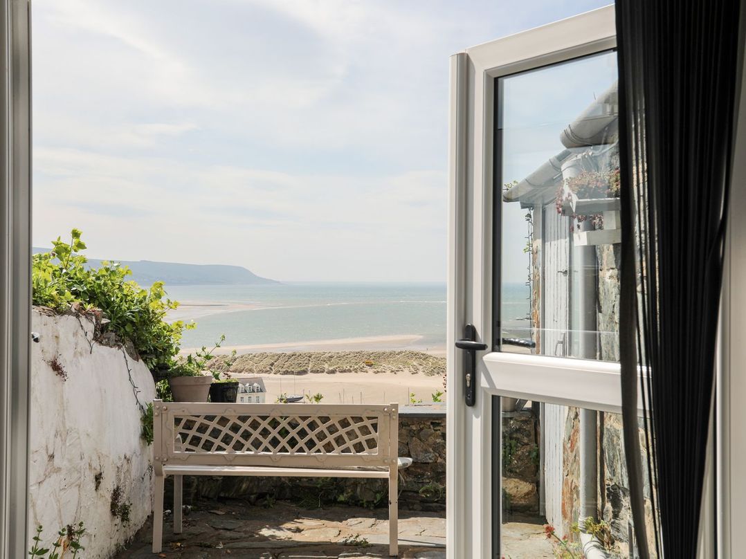 An outdoor area with a bench and a view of the sea at The Ingle in Barmouth