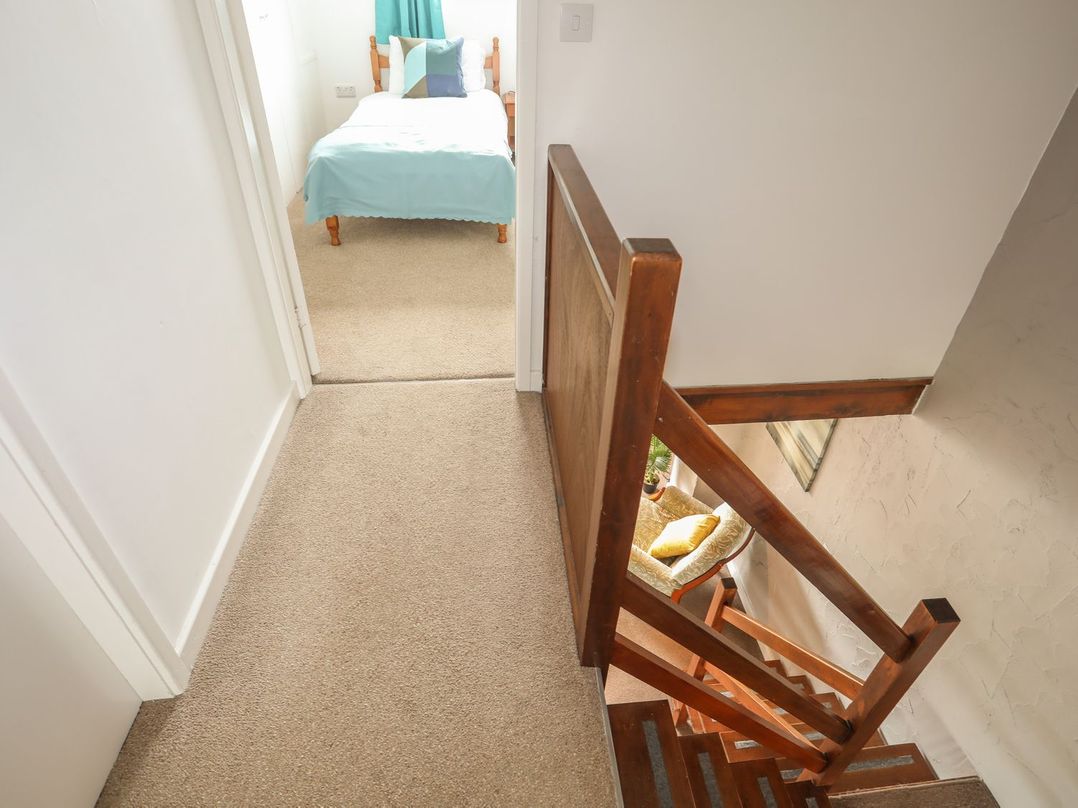 A hallway with a staircase leading down and a bedroom at Fadrun - 3 Ty'n Don