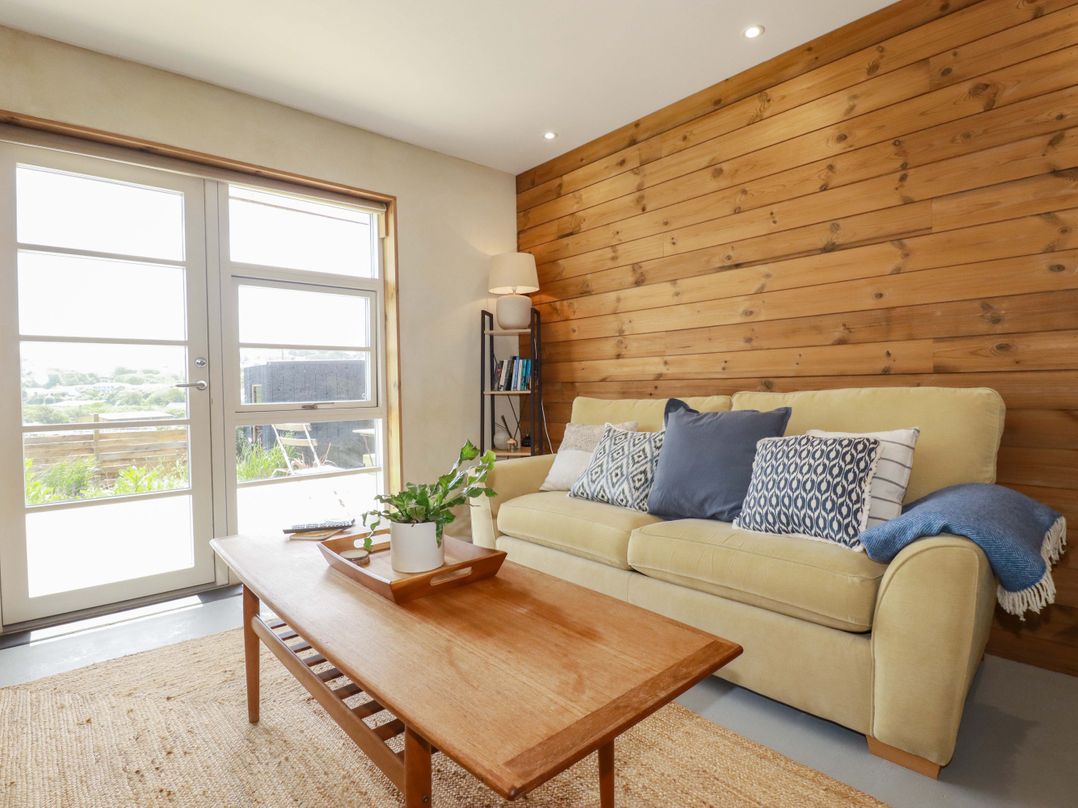 A living room with a sofa and coffee table at Teach Tra West in Perranporth