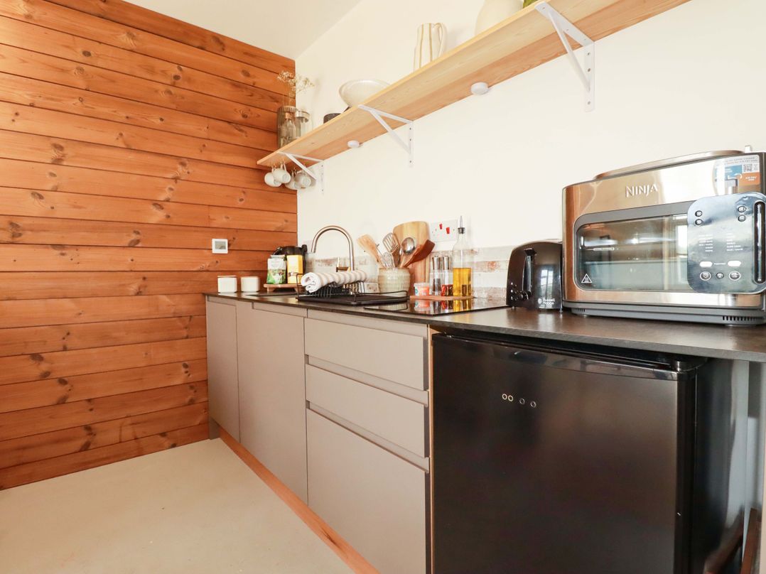 A kitchen with cabinets, sink, and appliances at Teach Tra West in Perranporth