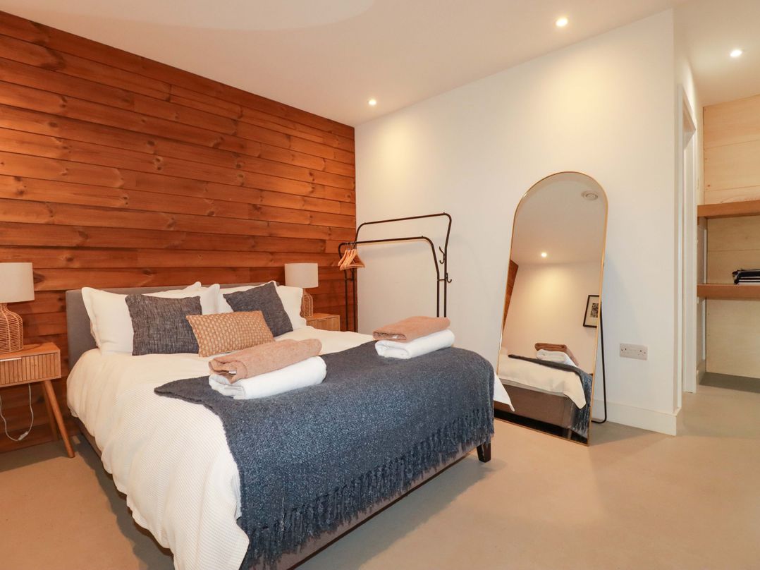A bedroom with a bed and wooden wall at Teach Tra West in Perranporth