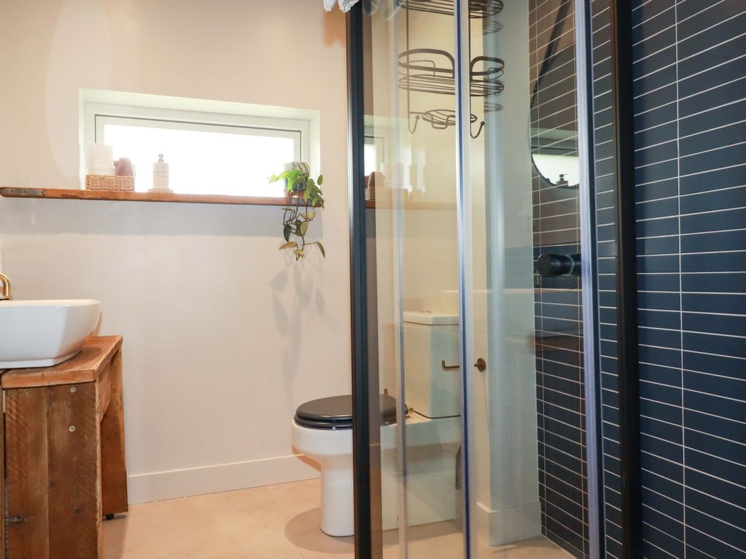 A bathroom with a shower, toilet, and sink at Teach Tra West in Perranporth