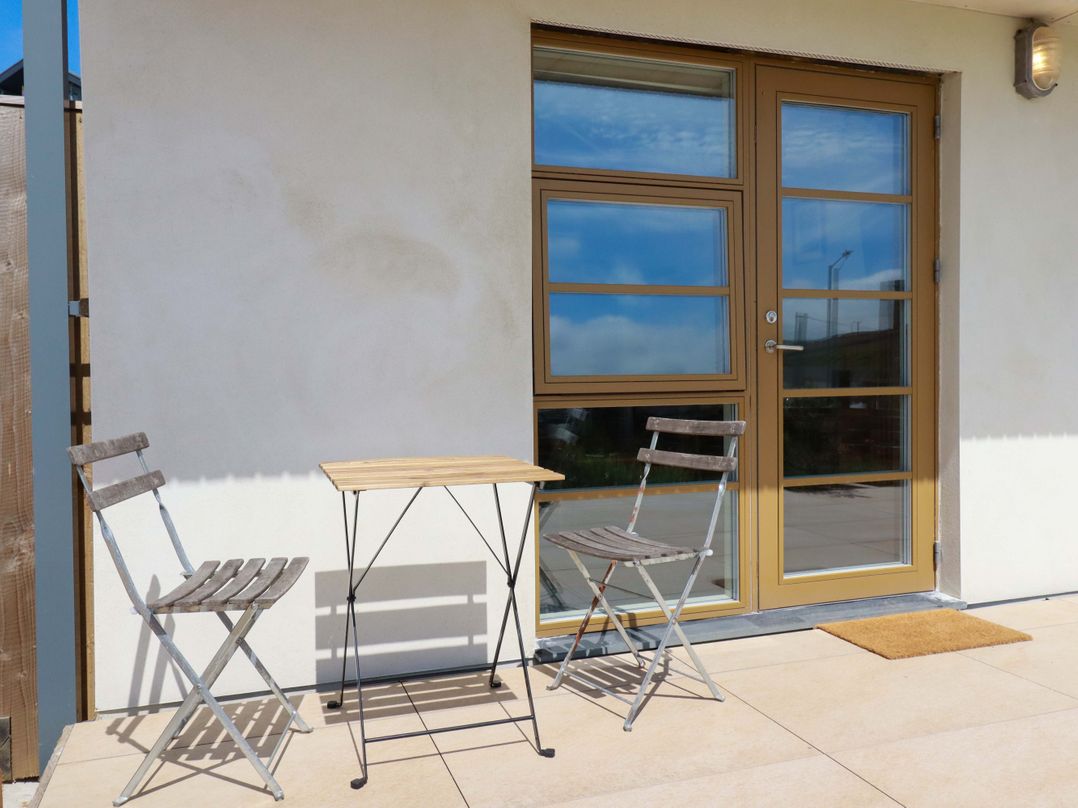 An outdoor seating area with a table and chairs at Teach Tra West in Perranporth