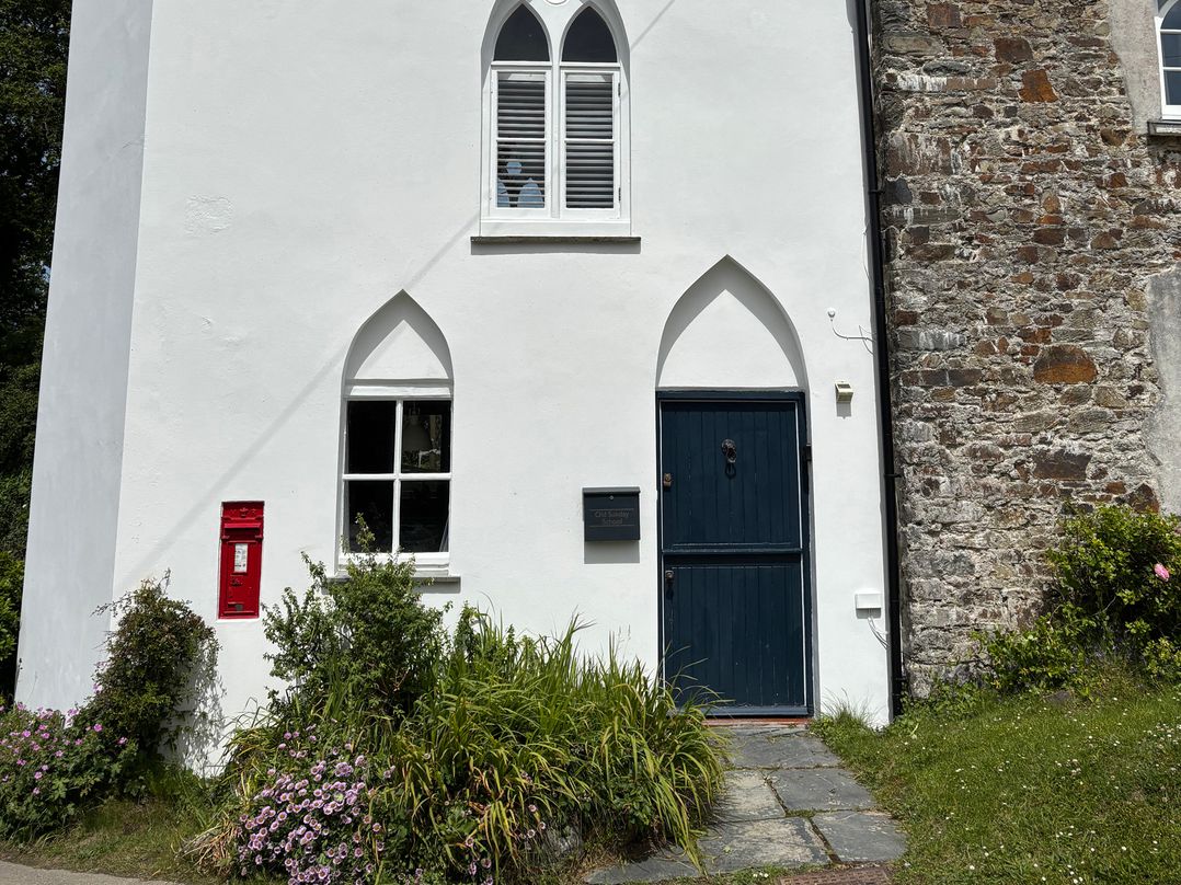 A white building with a blue door and red postbox at Old Sunday School Welcombe
