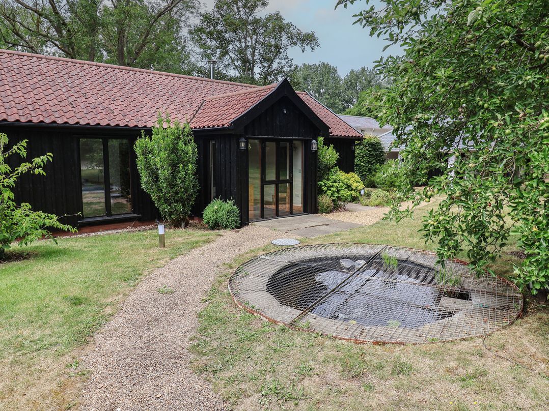 An outdoor area with a pond and a gravel path at Owl Cottage Kettleburgh near Framlingham
