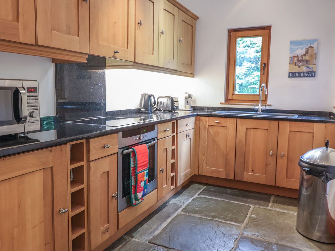 A kitchen with wooden cabinets and appliances at Owl Cottage in Kettleburgh near Framlingham