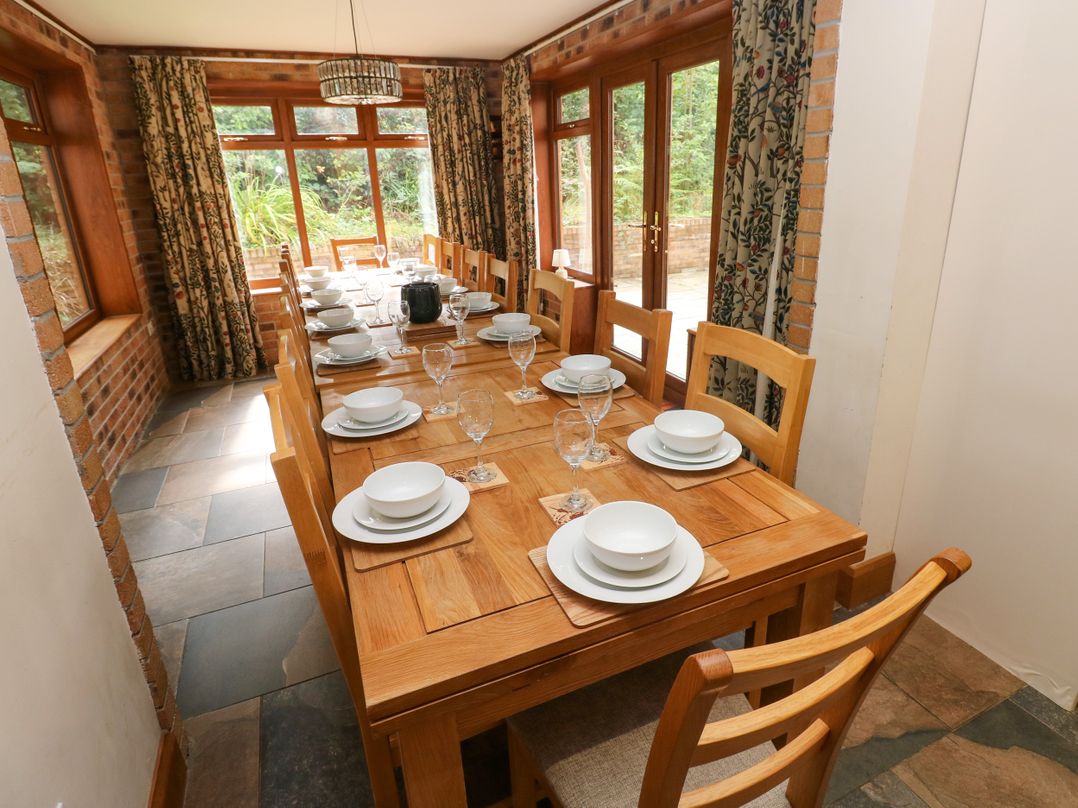 A dining room with a long table set for a meal at Ty-Gan Dderwen in Llangennech, Llanelli