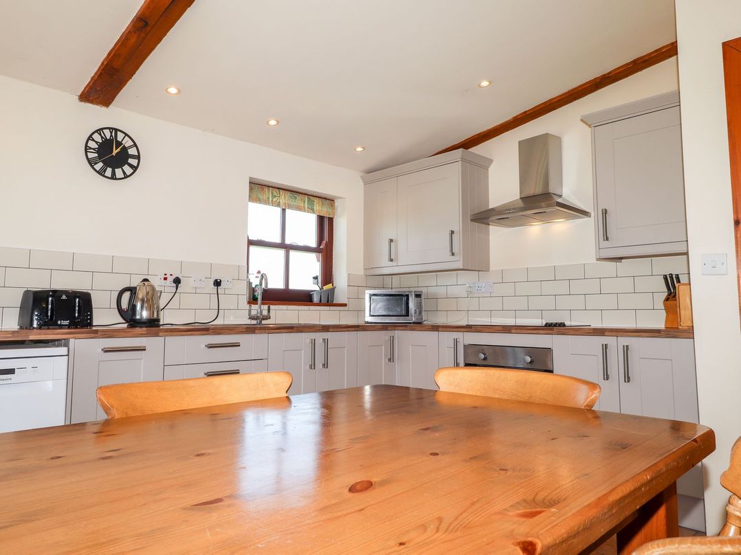 A kitchen with appliances and wooden table at Ty Cariad in Newport