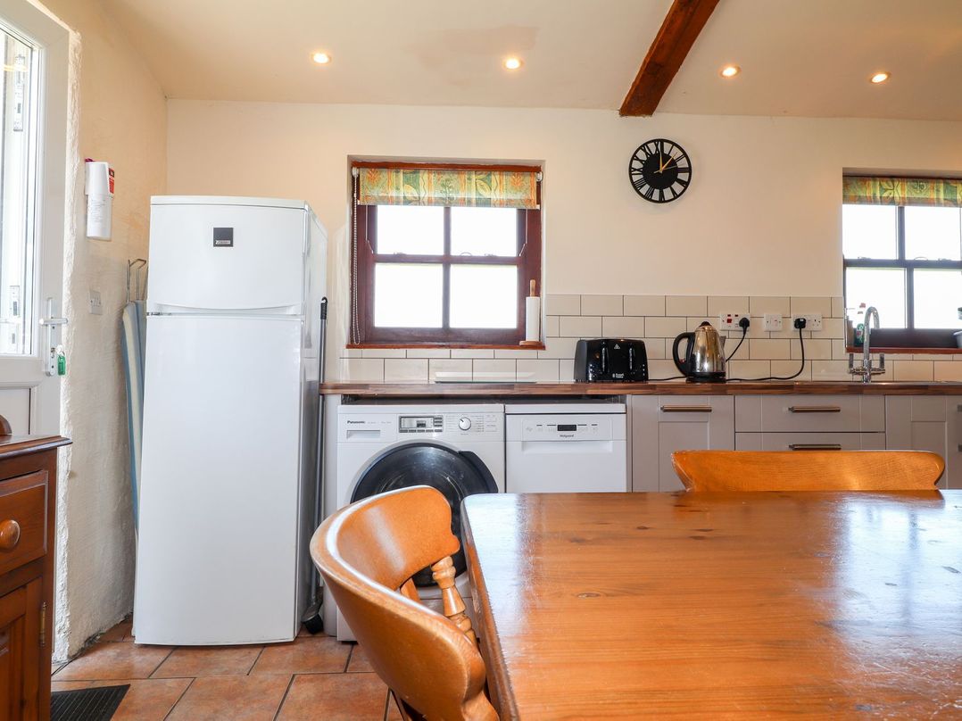 A kitchen with appliances and a dining table at Ty Cariad in Newport