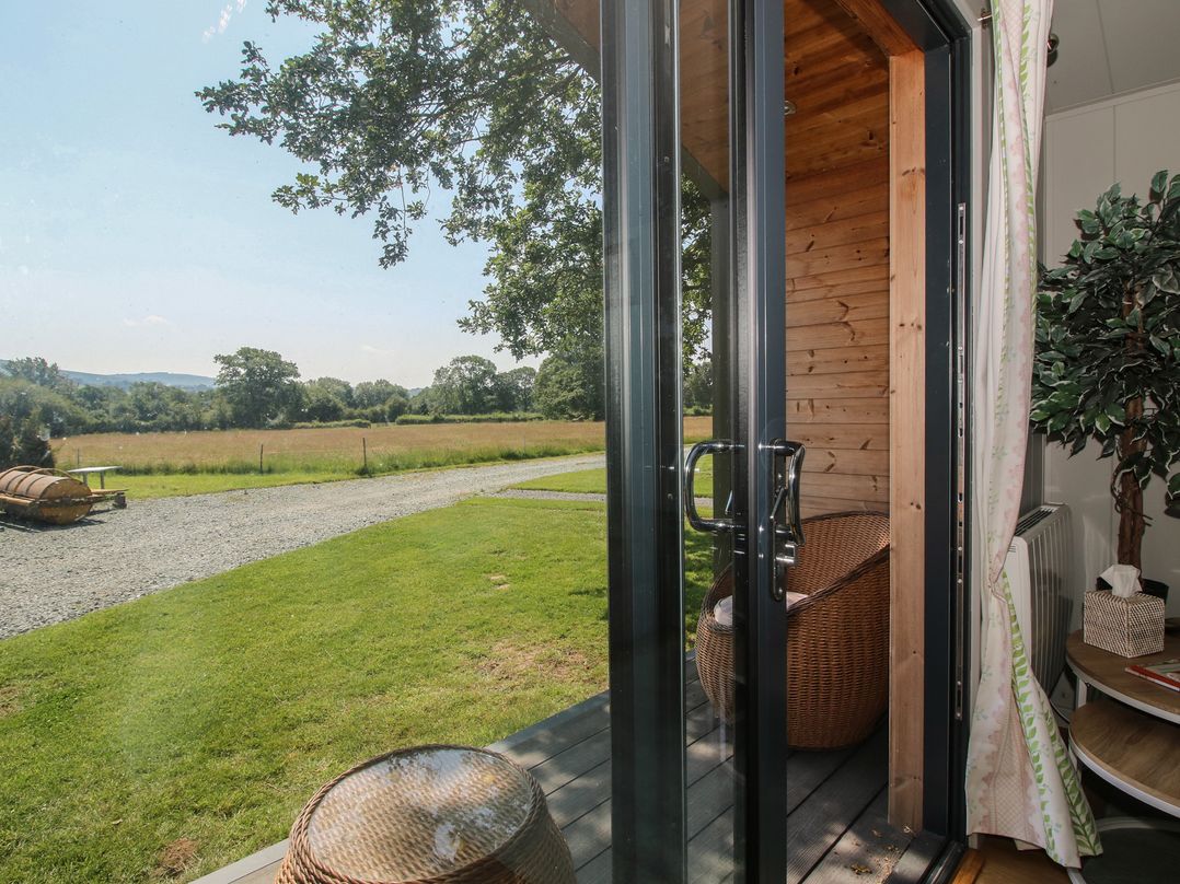 A view from a cabin door with a chair and table at Leafy Oaks Cabin in Munslow