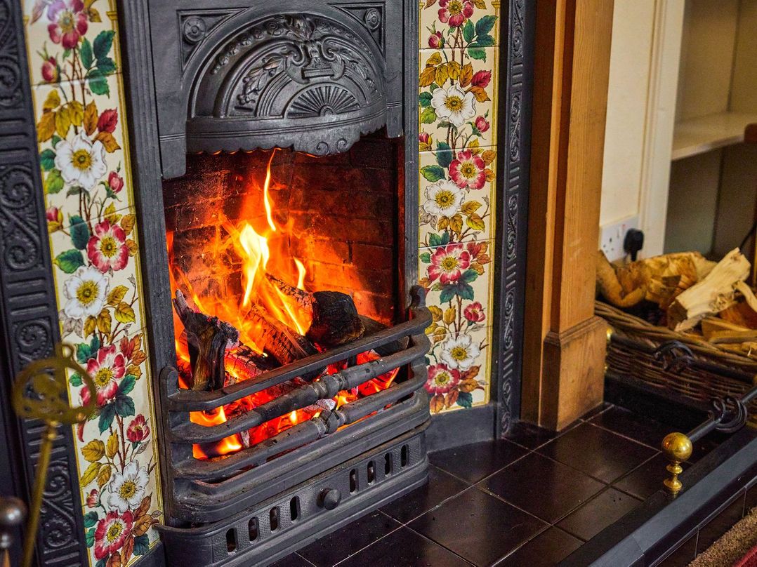 A fireplace with flames and logs at West Lodge Kirriemuir