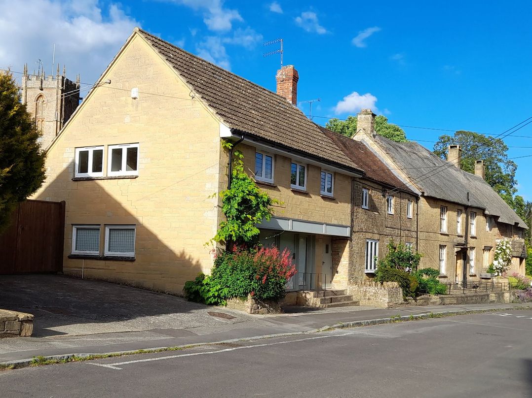 Houses along a street with a church in the background at Greenham Rise in Norton-Sub-Hamdon