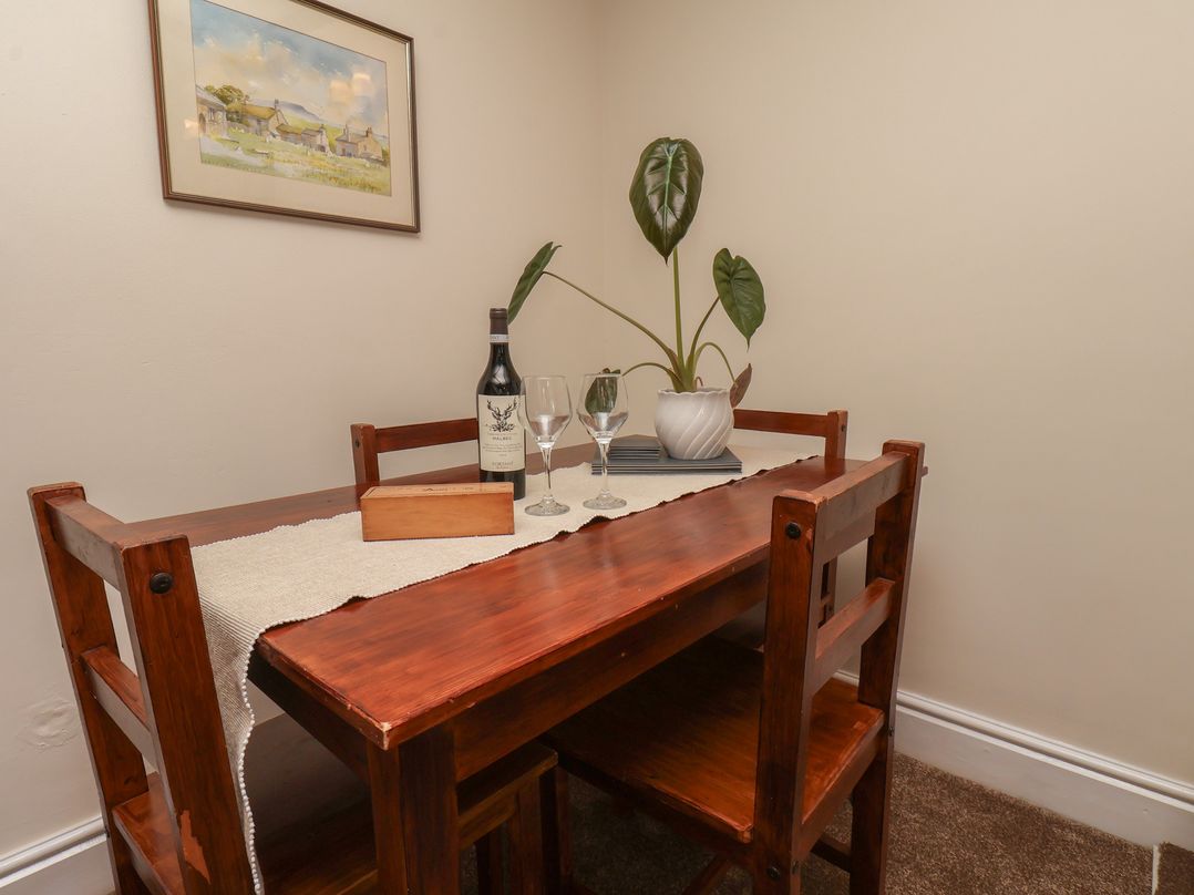 A dining area with a table, chairs, and a wine bottle at 4 Lilac Cottages Ainthorpe