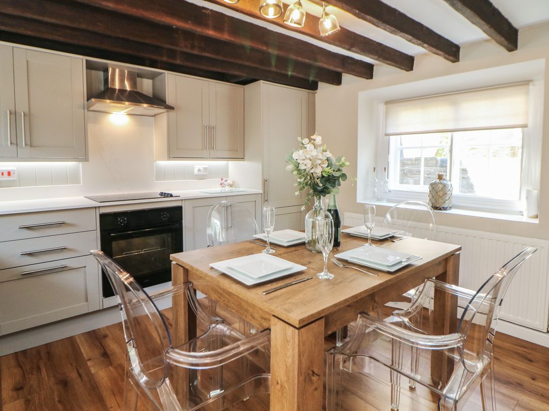 A kitchen with a wooden table and clear chairs at Lake Side Cottage in Wakefield
