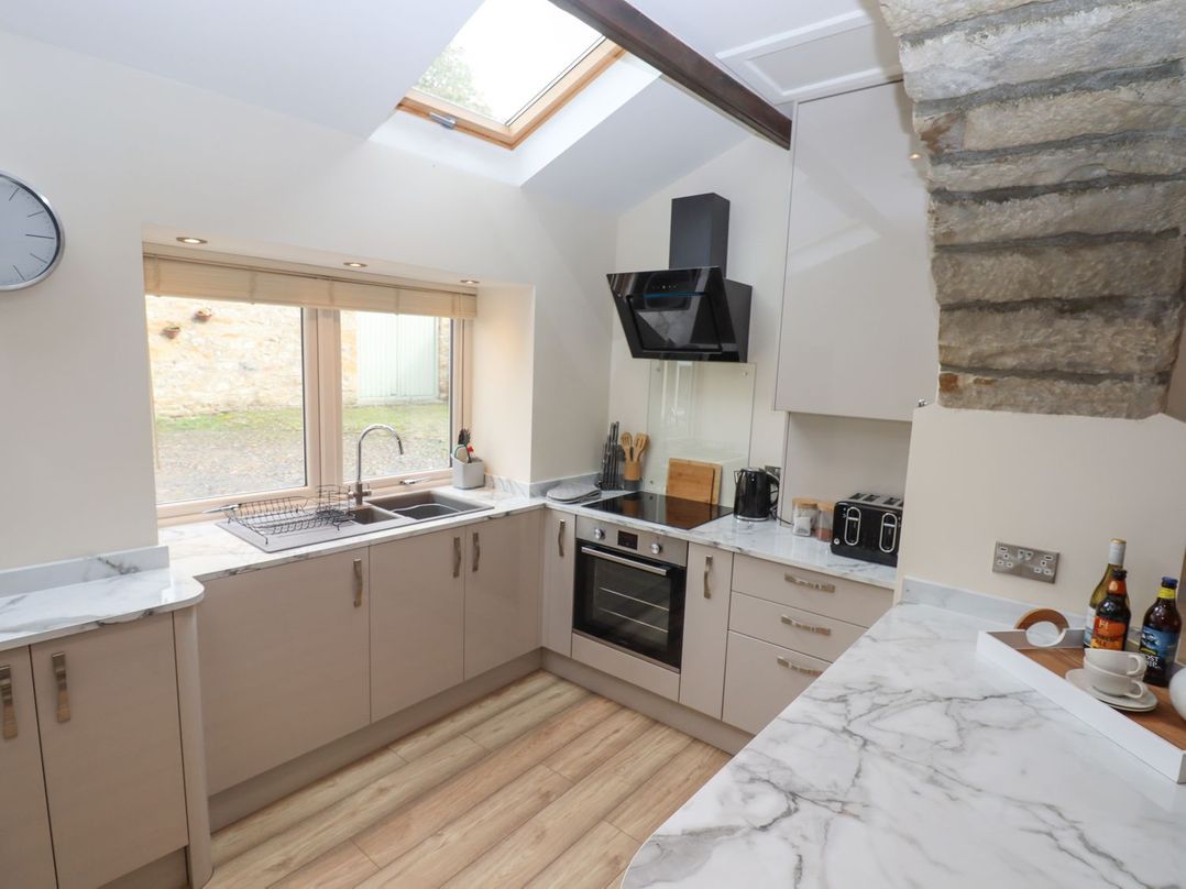A kitchen with a sink and modern appliances at 1 Grosvenor Farm Cottages Skipton