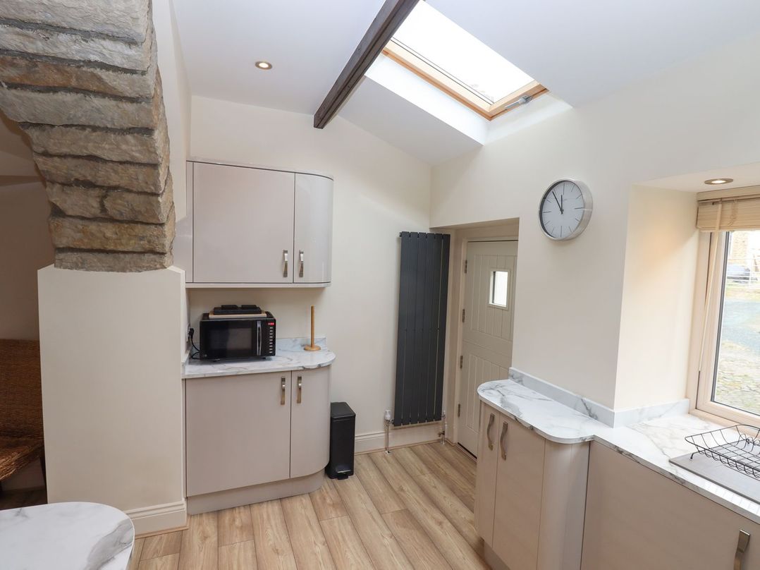A kitchen with cupboards and a microwave at 1 Grosvenor Farm Cottages Skipton