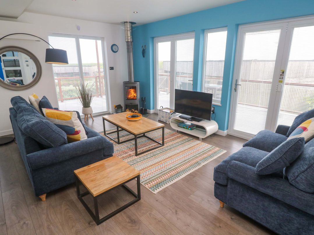 A living room with a sofa, coffee table and television at Pentewan - 67, Portreath