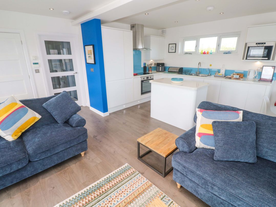 A living room with sofas and kitchen units at Pentewan - 67 Portreath