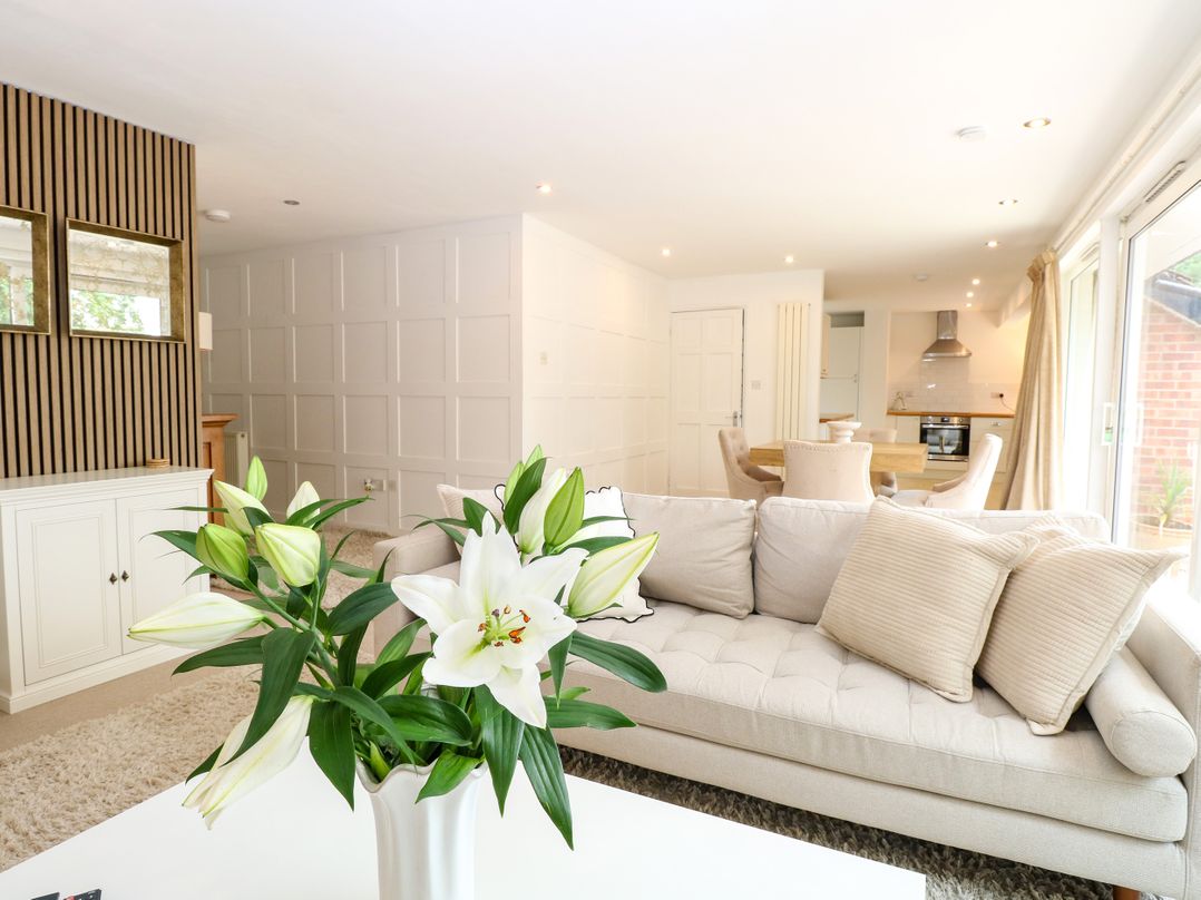 A living room with a sofa and vase of flowers at Three Ways in South Lopham near Garboldisham