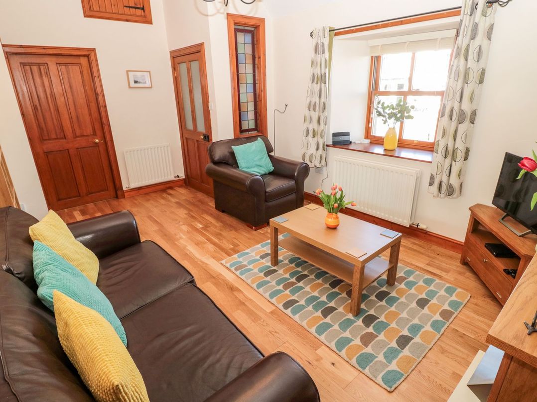 A living room with a sofa, coffee table, and armchair at Cygnet Cottage in Berwick-upon-Tweed