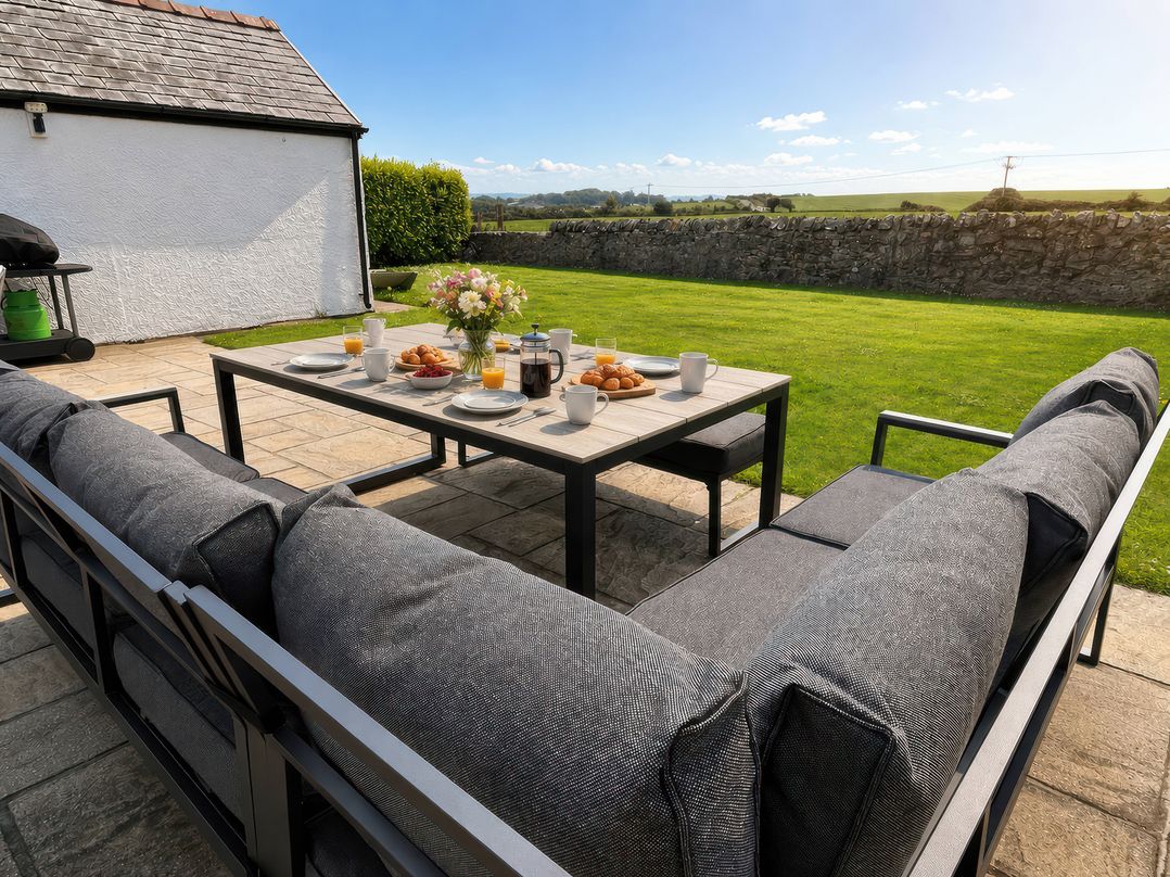 An outdoor seating area with a table set for breakfast at Bryniau in Morfa Nefyn