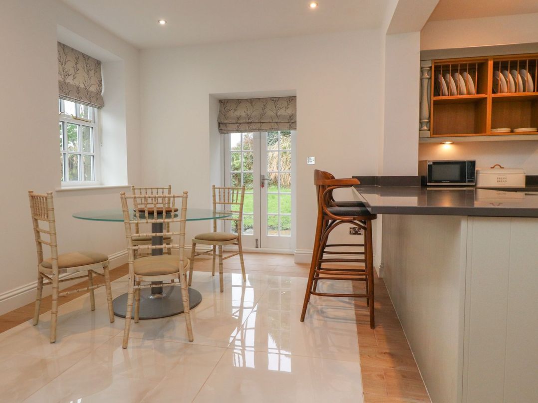 A dining room with a glass table and chairs at The Lodge House Dolphinholme near Galgate
