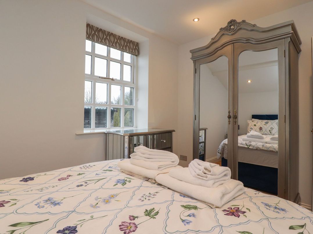 A bedroom with a bed and wardrobe at The Lodge House in Dolphinholme near Galgate